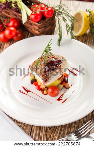 Cooked white fish fillet with colorful salad and ingredients on wooden table