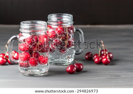 Two glasses of sweet cherry lemonade on black background