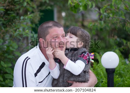 Street happy little daughter kissing daddy