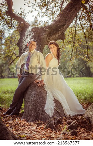 bride and groom in nature, near a large tree