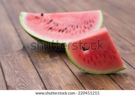 a piece of cut watermelon on a wooden background  , with a cut out heart shape