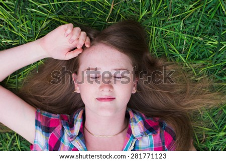 Portrait of a young girl lying on her back on the grass with his eyes closed