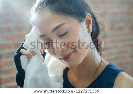 Asian girl exercising in gym she tired and She has sweat on her face.