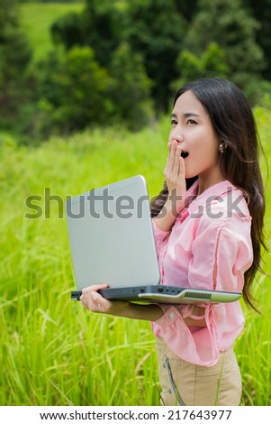 Asian woman in the forest holding a laptop surprise