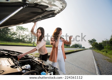 Asian woman broken car on the road is a phone and watch. Tell a car mechanic
