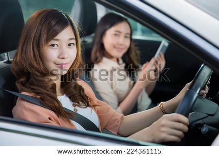 Asian woman was driving with a friend to play the tablet