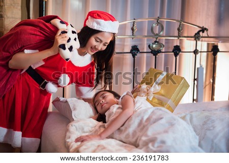 santa claus lady give gifts to children who were sleeping on the bed in Christmas day