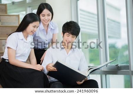 Asian students Watching a friend\'s huge volumes of books on the stairs