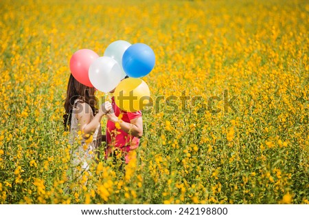 Couple kissing in the garden yellow flowers. Valentine\'s Day Helps shield the eyes with balloons
