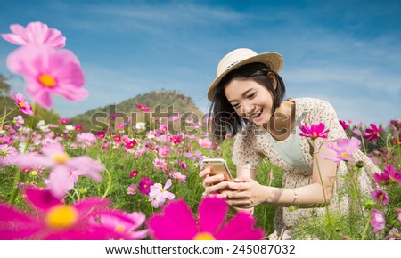 Asian woman using a smartphone photographing flowers in the flower garden