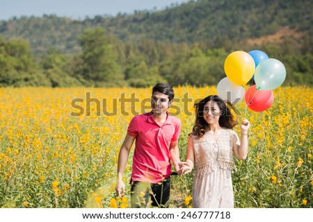 Couple playing in the garden flowers yellow balloons. Both happy and smiling on Valentine's Day