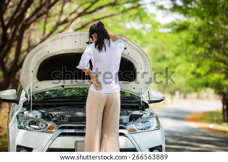 Women spection She opened the hood Broken car on the side See engines that are damaged or not.