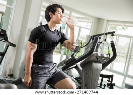 Asian men are drinking clean water While cycling exercise at the gym.