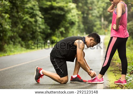 Couples runners Jogging Man tie his shoes to his girlfriend Couples runners Jogging Man tie his shoes to his girlfriend