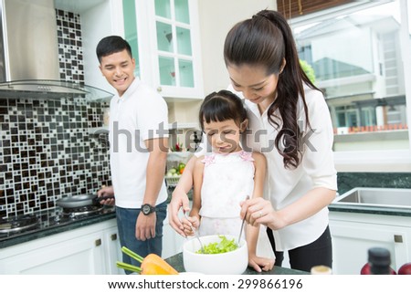 Mother and son are helping to make a salad in the kitchen