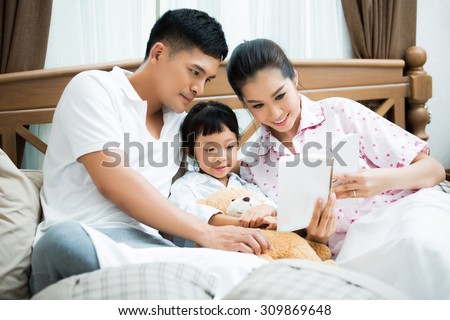 Asian family Fathers are teaching their children reading homework on the bed