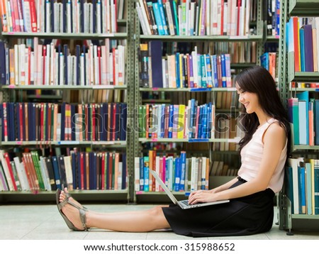 Asian student in the library.she is using a computer finding information