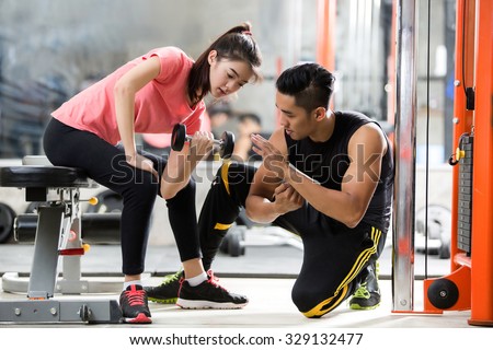 Trainer men are teaching Asian woman lifting a dumbbell. In the way they exercise in the gym.