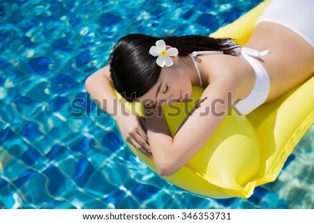 Asian young girl wear bikini swim at the resort. she was sleeping on a rubber raft floating.