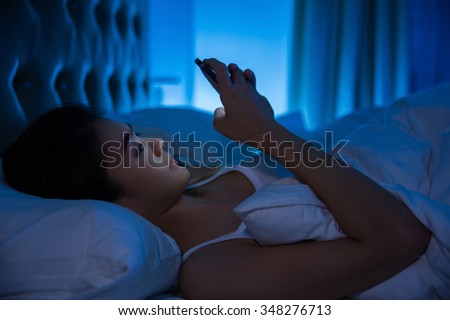 Asian women are using the smart phone on the bed before she sleeping at night. Mobile addict concept.