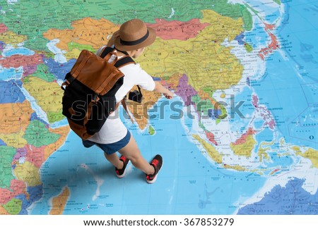 Women traveler Is planning a tour her standing on the world map.She points to the map