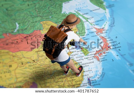 Women traveler Is planning a tour her standing on the world map.she points to Japan