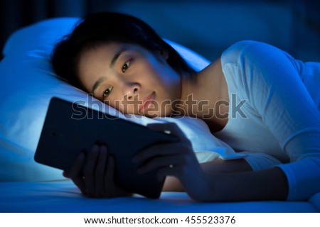 Asian women are using the tablet on the bed before she sleeping at night. Mobile addict concept.
