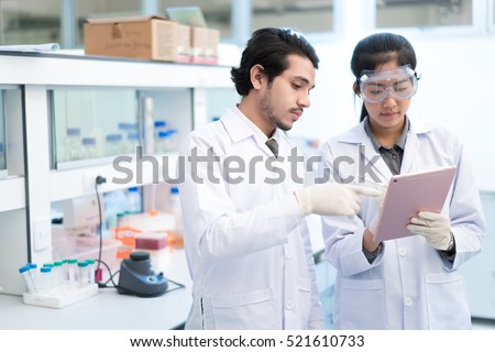 Scientists asian in the laboratory they use a tablet recording the results.