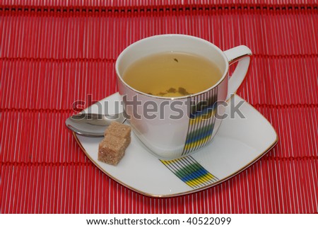 Cup of green on a red bamboo with two pieces of sugar