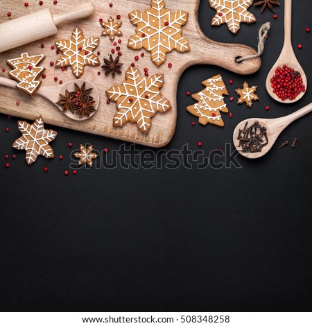 christmas homemade gingerbread cookies, spices and cutting board on black background with copy space for text top view. holiday, celebration and cooking concept. new year and christmas postcard