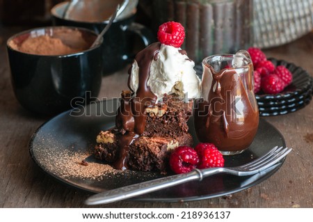 Chocolate pecan brownies with chocolate sauce, ice cream and raspberries, selective focus