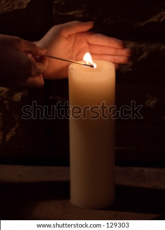 person lighting a candle in the dark