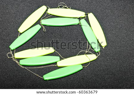 Green and yellow wooden necklace on black background