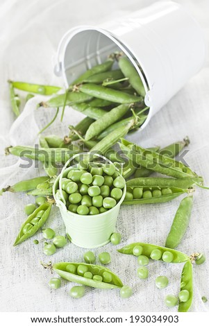 Green pea and pea pods in small buckets. High key.