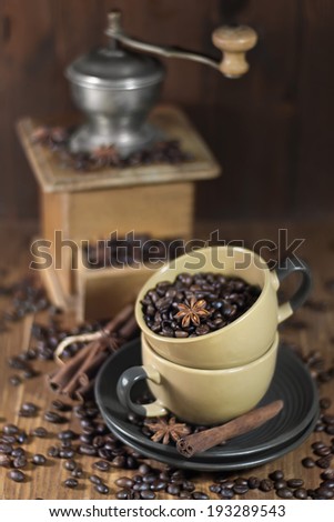 Roasted coffee beans with star anise and cinnamon in the ceramic coffee mugs with old coffee mill. Selective focus.