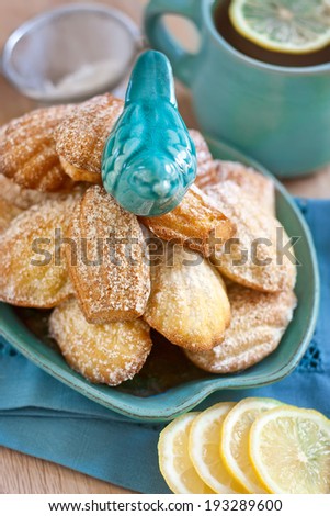 Little ceramic teal bird on heap of madeleines (kind of French traditional cookies). Selective focus.