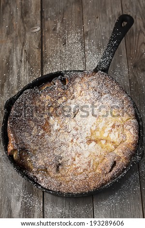 Big dutch baby pancake on iron pan, dusted with powdered sugar