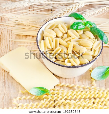 Mix of pasta, basil and parmigiano. Selective focus. Square format.