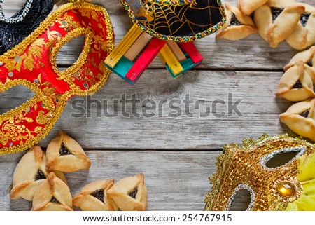 Hamantaschen cookies or Haman\'s ears, noisemaker and carnival masks for Purim celebration (jewish holiday). Copy space background.