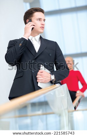 Great deal on the mobile phone. Confident and motivated businessman is talking on a cell phone, holding a tablet and looks forward