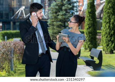 Some good news on the phone. Two young and motivated business partners are discussing last project issues together. Businessman is asking for last news on the mobile phone