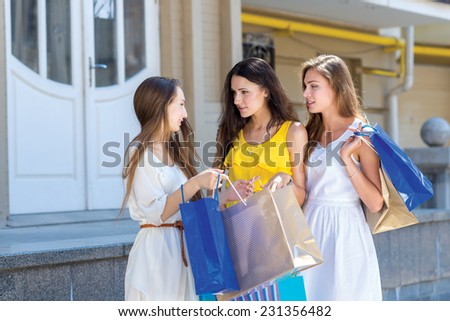 Lets looks for something else. Three young and pretty girls are standing with shopping bags and chatting about further shopping choices