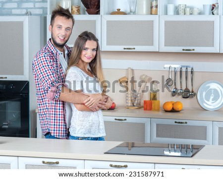Cooking with love. Beautiful pair is standing on the kitchen and preparing for cooking tasty dinner