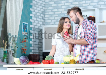 Looking for the tasty and healthy recipes. Beautiful pair is standing on the kitchen and making tasty salad for their delicious meal