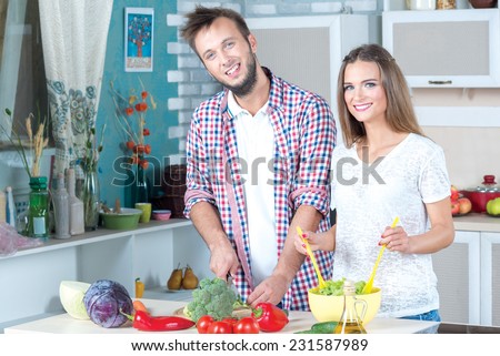 Ideal healthy meal preparation. Beautiful pair is standing on the kitchen and cooking healthy and delicious dinner.