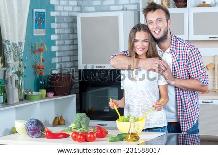 Good emotions while cooking. Beautiful pair is standing on the kitchen is making healthy food on the kitchen. Both are smiling, while food looks delicious