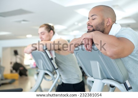 Good rest after good workout. Two handsome guys are having rest after great sport workout on treadmill in a gym. Both sportsmen are standing on a treadmill