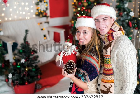Love on Christmas. Loving couple is standing in the festive New Year living room and smiling. Great time just before Christmas