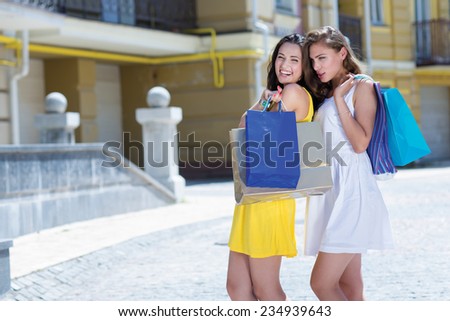 Great deal while shopping. Two attractive young women are standing on the street with shopping bags. Girls are happy and smiling
