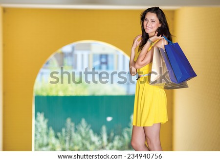 Good deal on shopping sales. Attractive young women is standing with shopping bags on the street and smiling, while looking forward
